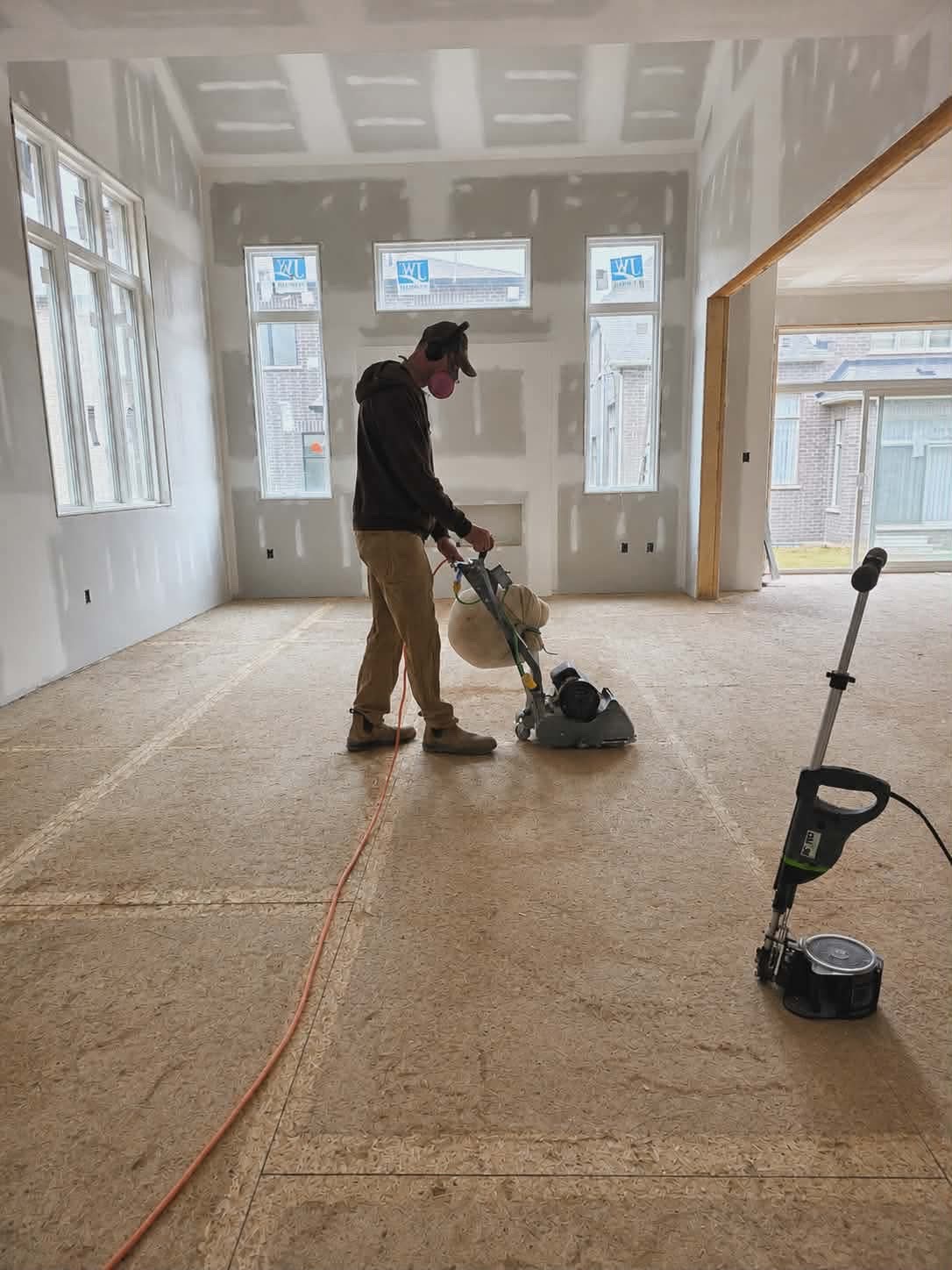 Operator using an 8-inch drum sander on a subfloor