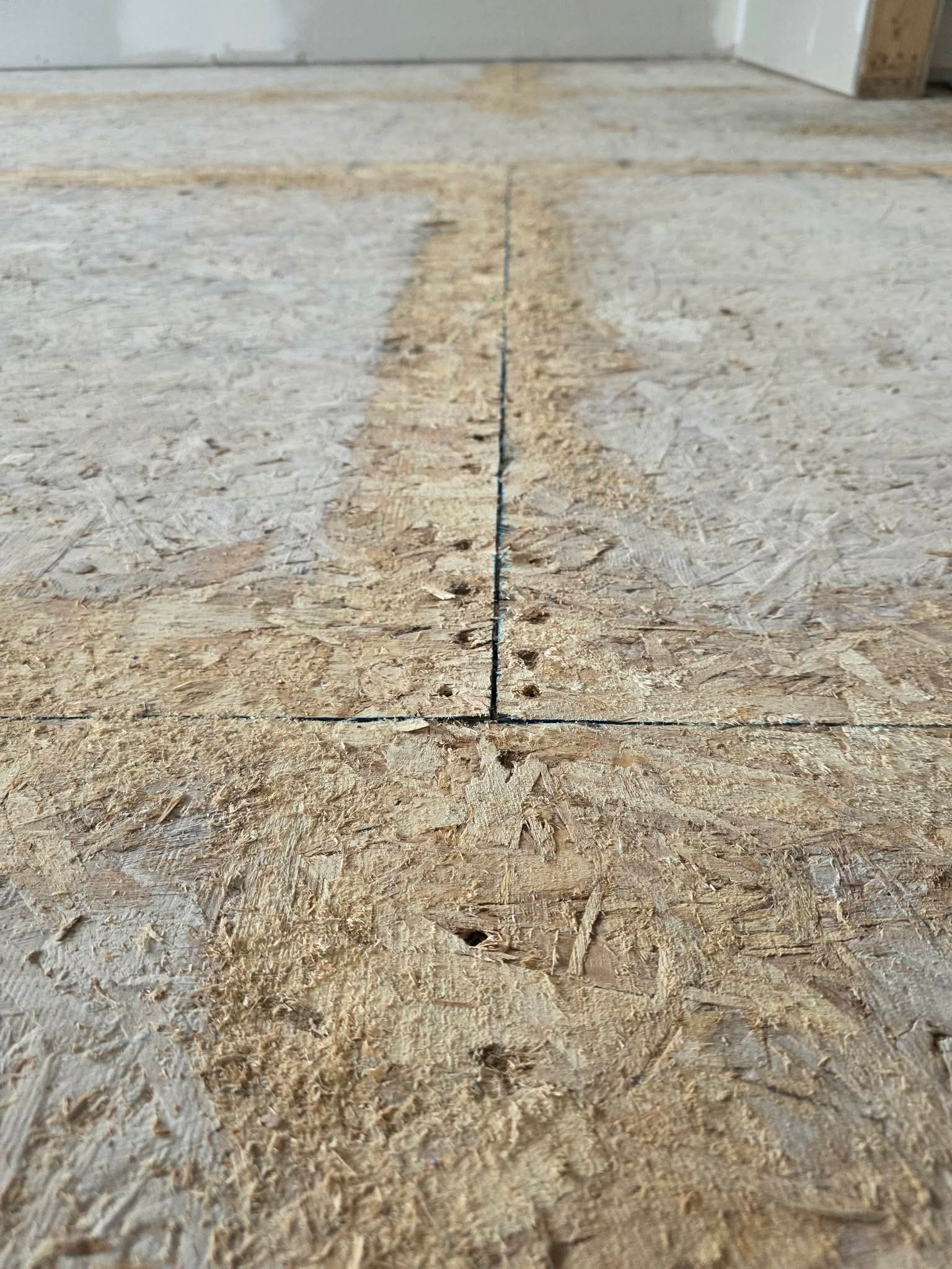 Close-up of sanded subfloor seams and screw lines