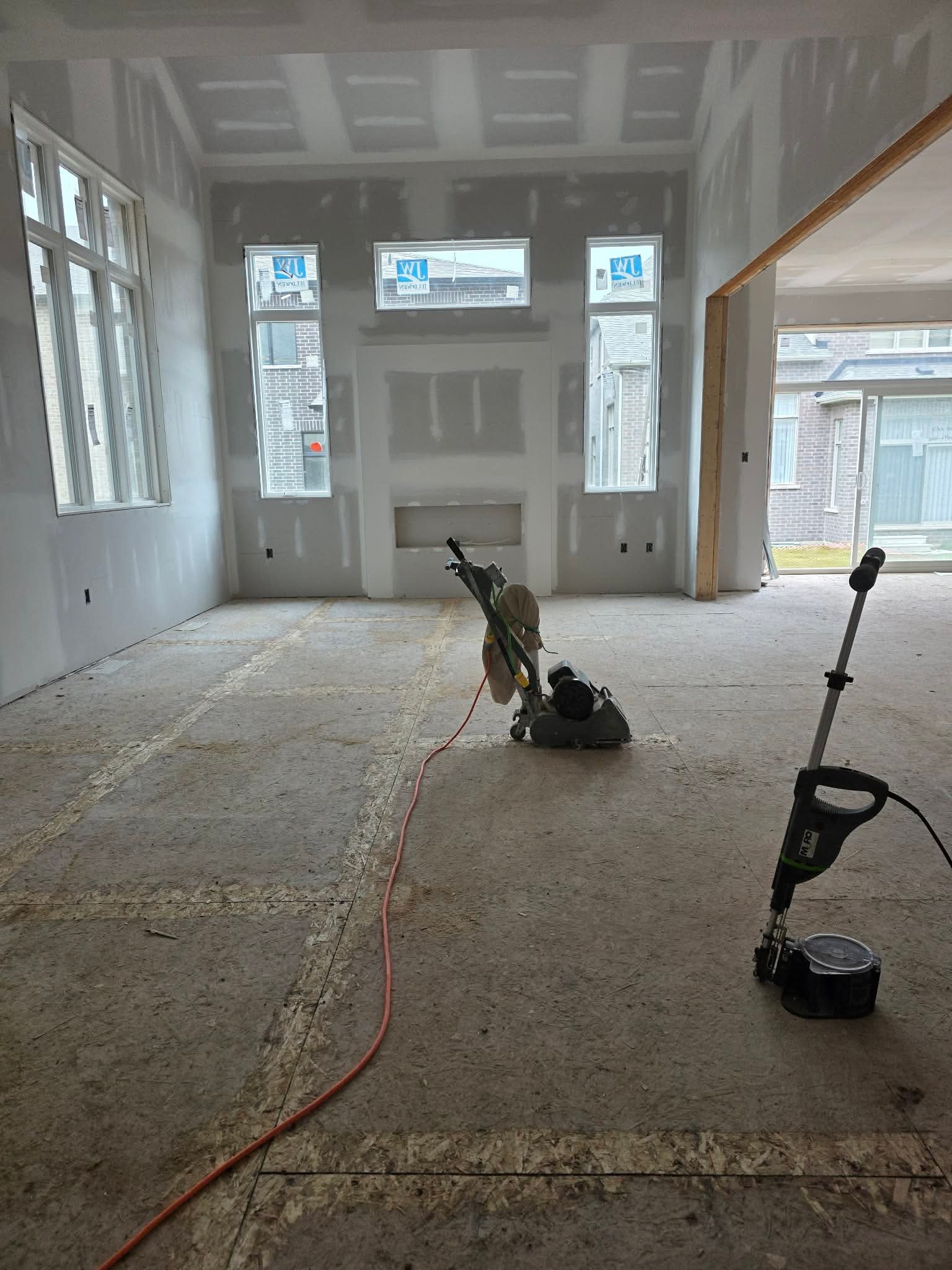 Wide view of subfloor screw and sand job site with drum sander and Muro screw gun